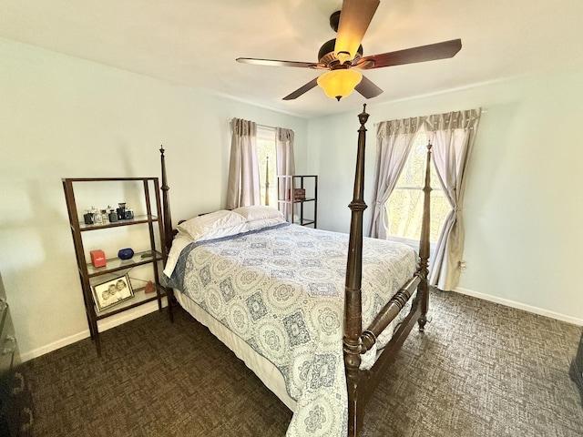 bedroom with ceiling fan, dark carpet, and multiple windows