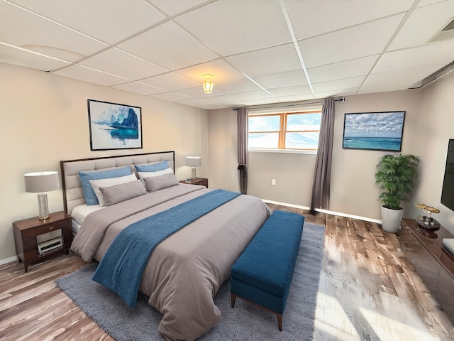 bedroom with hardwood / wood-style floors and a paneled ceiling