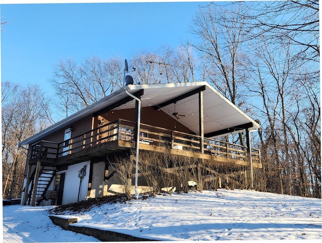 view of snowy exterior with ceiling fan and a wooden deck