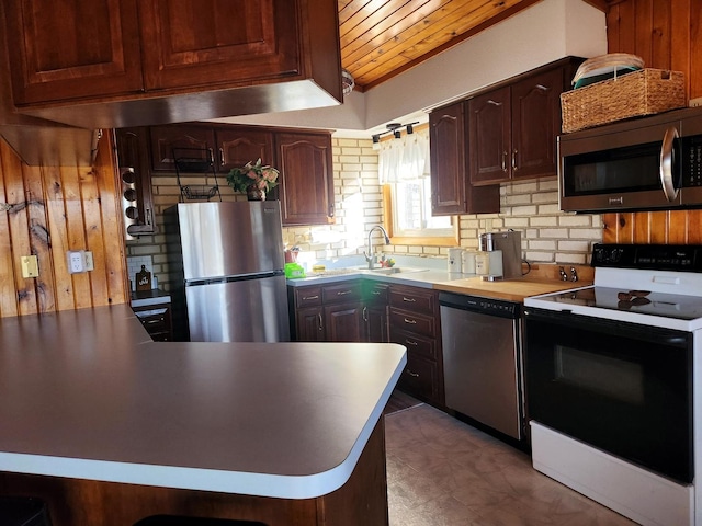 kitchen featuring wood ceiling, kitchen peninsula, appliances with stainless steel finishes, dark brown cabinetry, and sink