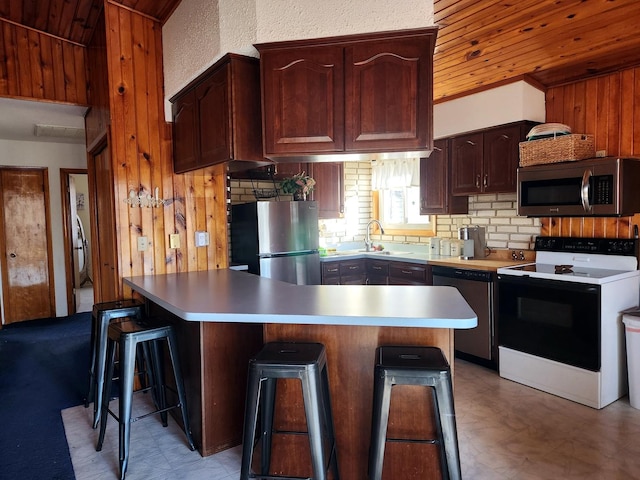 kitchen featuring a center island, sink, wood ceiling, appliances with stainless steel finishes, and a kitchen breakfast bar