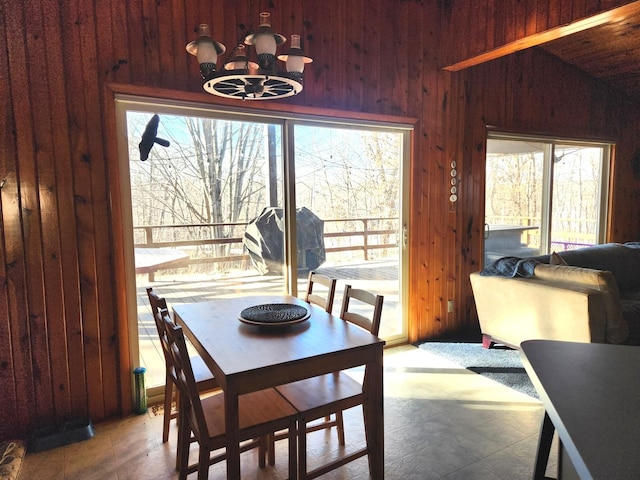 dining room with wood walls and a chandelier