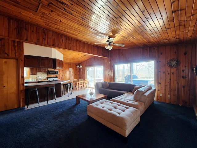 living room with ceiling fan, wooden ceiling, light colored carpet, and wood walls