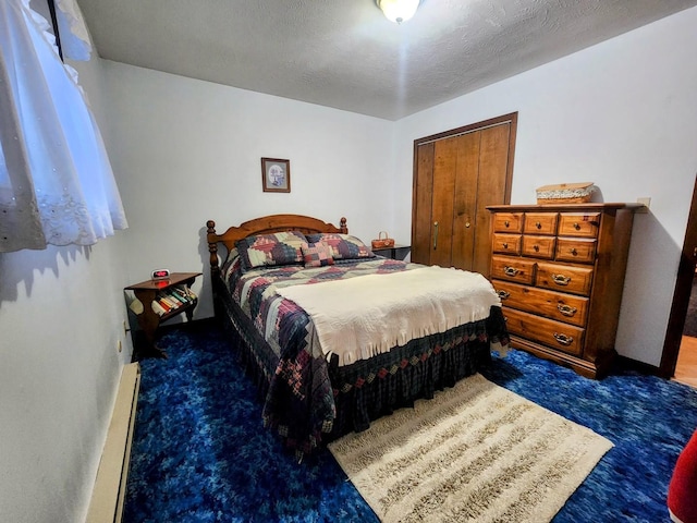 bedroom with baseboard heating, a textured ceiling, a closet, and dark colored carpet