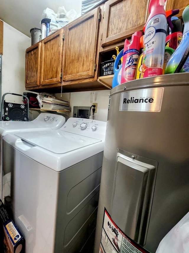 clothes washing area with cabinets, washer and clothes dryer, and water heater