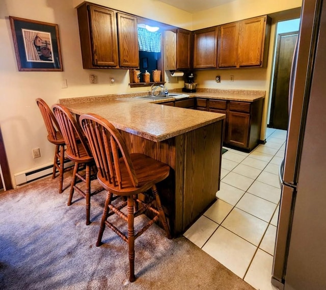 kitchen with stainless steel fridge, kitchen peninsula, a breakfast bar area, and light tile patterned flooring