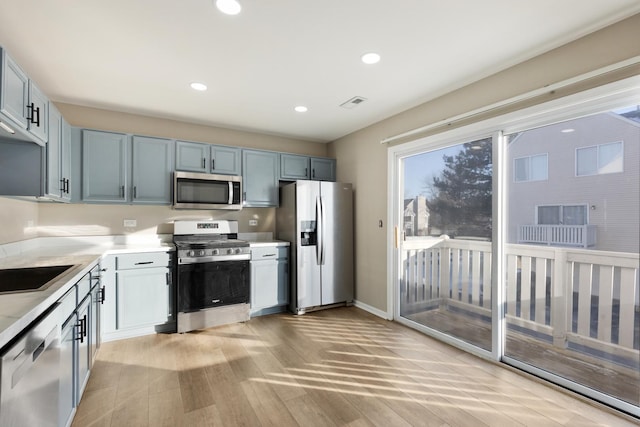 kitchen featuring appliances with stainless steel finishes, sink, and light hardwood / wood-style flooring