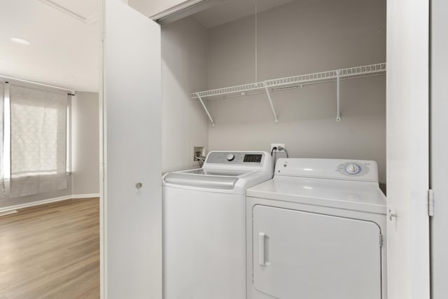 clothes washing area featuring independent washer and dryer and light hardwood / wood-style flooring