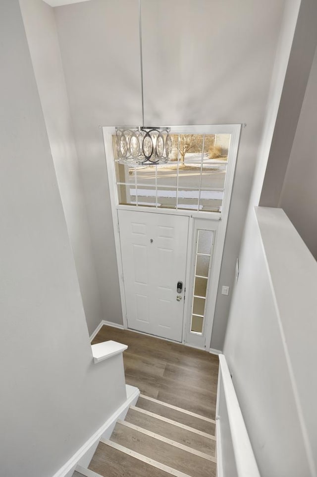 stairway with wood-type flooring and an inviting chandelier