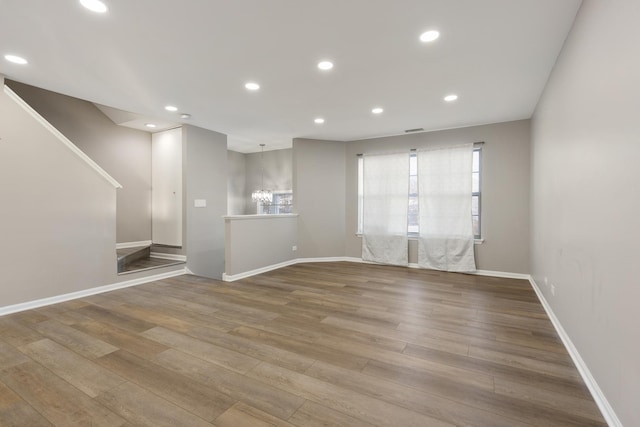 unfurnished living room with a chandelier and hardwood / wood-style floors