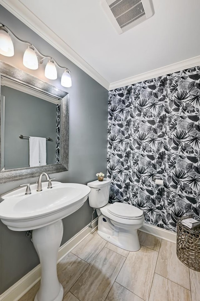 half bath with toilet, baseboards, visible vents, and crown molding