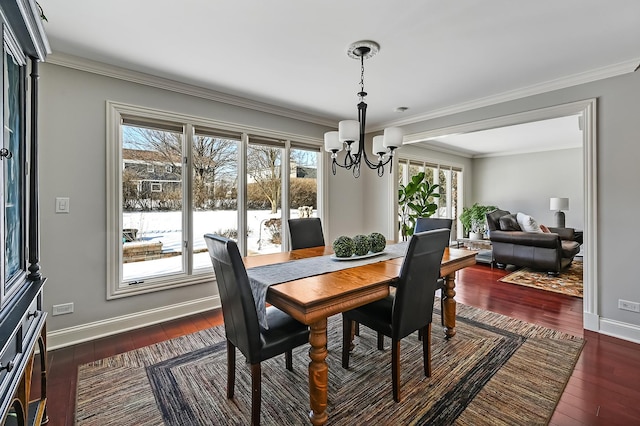 dining area featuring dark wood-style floors, baseboards, ornamental molding, and a notable chandelier