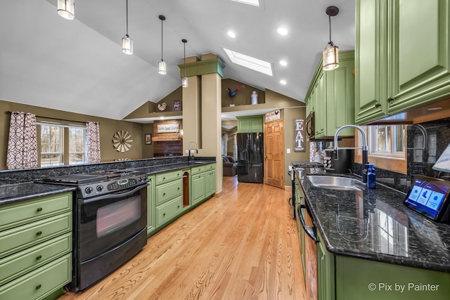 kitchen with vaulted ceiling with skylight, pendant lighting, black appliances, sink, and green cabinets