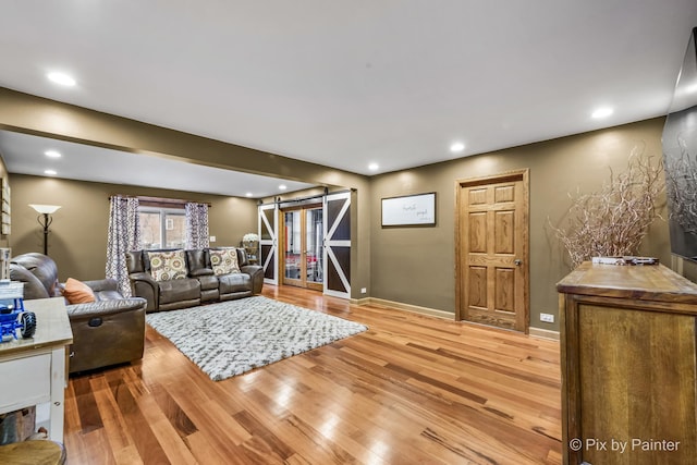 living room with a barn door and light hardwood / wood-style floors