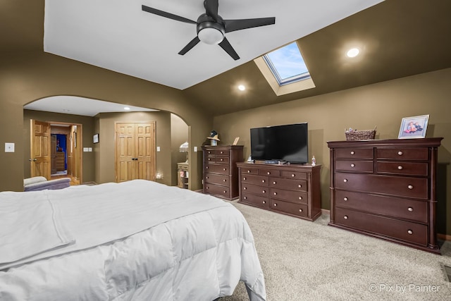 carpeted bedroom featuring ceiling fan, a closet, and lofted ceiling with skylight