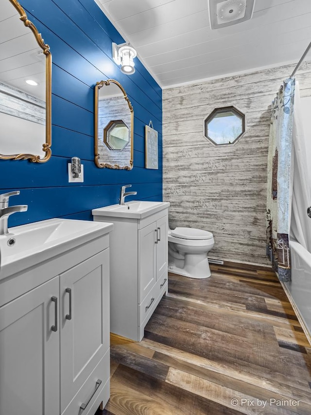 full bathroom with toilet, vanity, shower / bath combo, wooden walls, and hardwood / wood-style flooring