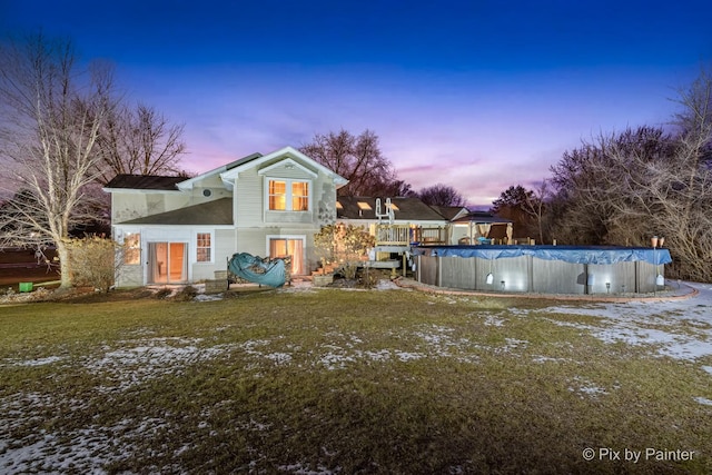 back house at dusk with a covered pool and a yard