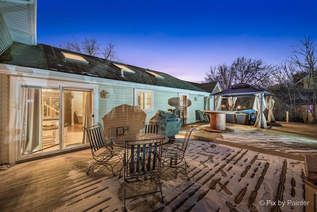 deck at dusk featuring a gazebo