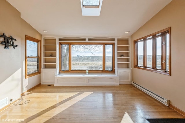 empty room featuring built in shelves, light wood-style flooring, a baseboard heating unit, baseboards, and lofted ceiling with skylight