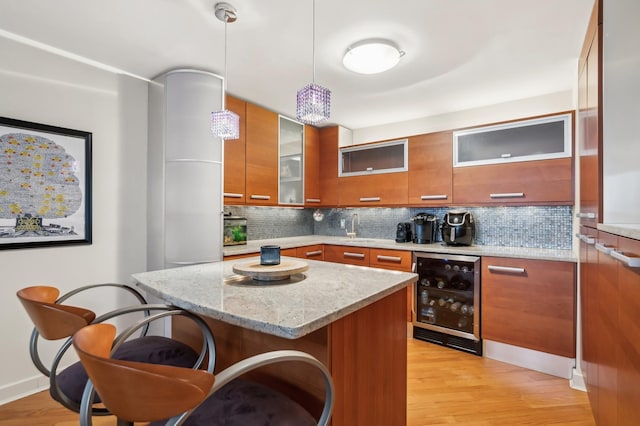 kitchen featuring pendant lighting, beverage cooler, a kitchen breakfast bar, a center island, and light stone counters