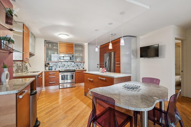 kitchen featuring a breakfast bar, a center island, hanging light fixtures, stainless steel appliances, and decorative backsplash