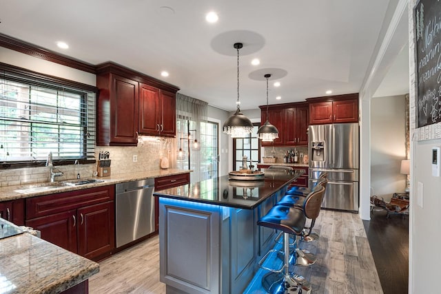 kitchen with sink, pendant lighting, stainless steel appliances, and a kitchen island