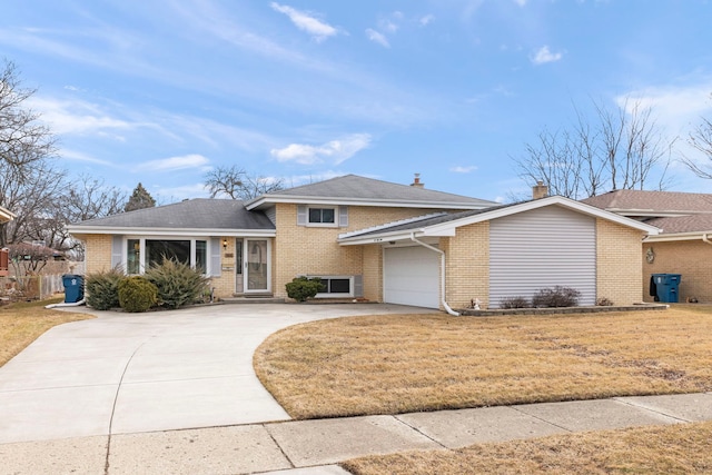 split level home with driveway, an attached garage, a front lawn, and brick siding