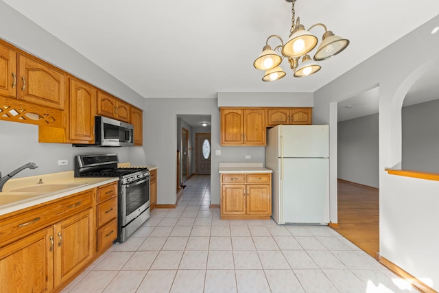 kitchen with appliances with stainless steel finishes, brown cabinetry, and light countertops