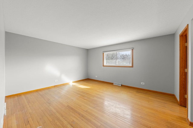 unfurnished room featuring light wood finished floors, visible vents, baseboards, and a textured ceiling