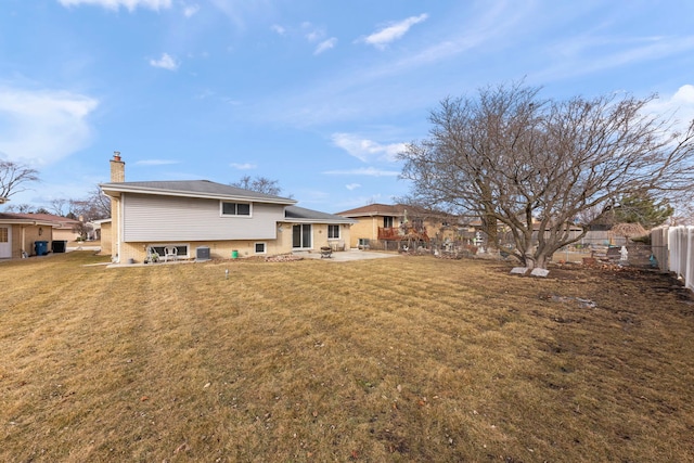 rear view of house featuring a yard, a patio, a chimney, and fence