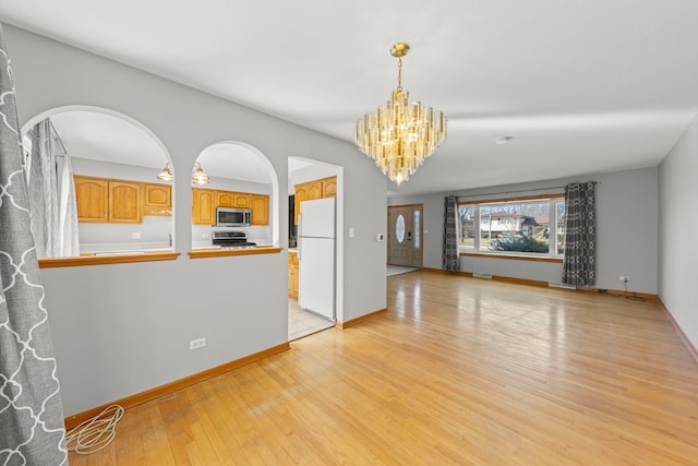 unfurnished living room with light wood-type flooring, baseboards, and a notable chandelier