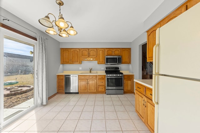 kitchen with light tile patterned floors, light countertops, appliances with stainless steel finishes, a sink, and a chandelier