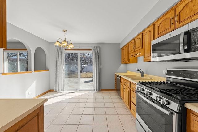 kitchen with stainless steel appliances, a sink, light countertops, and brown cabinets