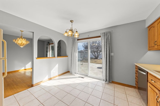 unfurnished dining area with light tile patterned floors, baseboards, and an inviting chandelier