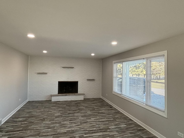 unfurnished living room featuring a brick fireplace and dark hardwood / wood-style flooring