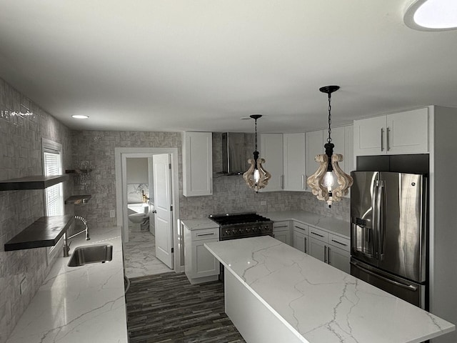 kitchen with gas stove, sink, white cabinetry, stainless steel fridge with ice dispenser, and pendant lighting