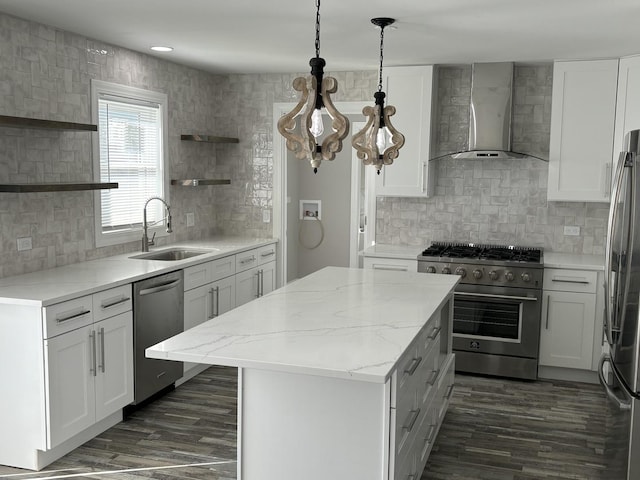 kitchen with wall chimney range hood, sink, appliances with stainless steel finishes, white cabinets, and a kitchen island