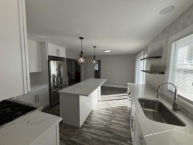 kitchen with sink, white cabinetry, a center island, stainless steel fridge, and light stone countertops