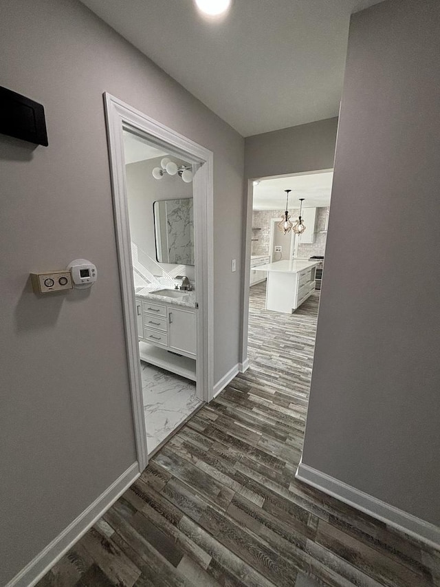 hall with dark hardwood / wood-style flooring, sink, and a chandelier