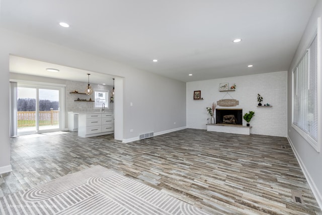 38W715 Huntley Rd, West Dundee, IL 60118 - unfurnished living room featuring wood finished floors, a fireplace with raised hearth, and recessed lighting