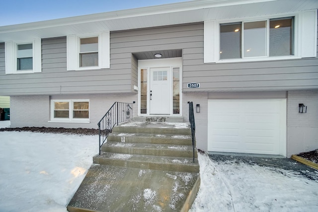 snow covered property entrance with a garage