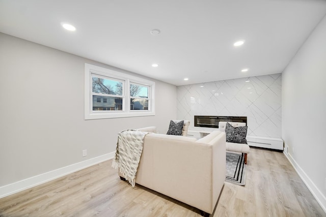 living room with a large fireplace and light hardwood / wood-style flooring