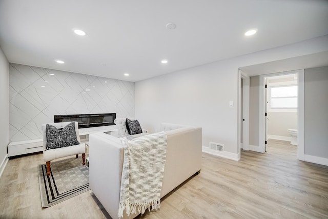 living room with a large fireplace and light hardwood / wood-style flooring