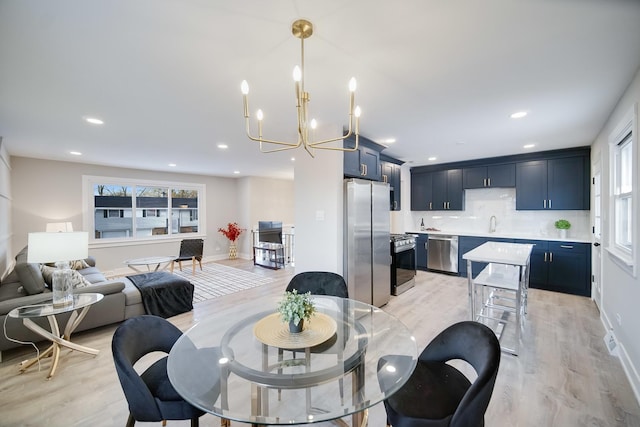 dining space with light wood-type flooring, an inviting chandelier, and sink