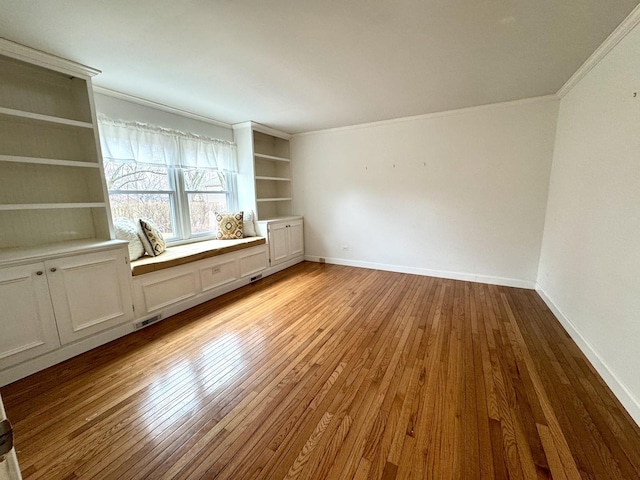 unfurnished room with visible vents, ornamental molding, baseboards, and wood-type flooring