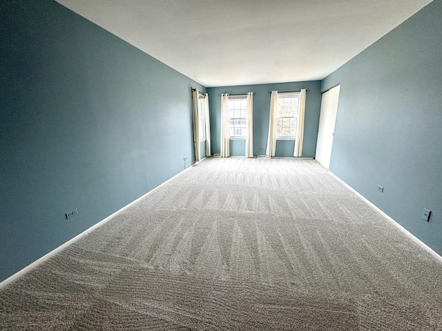 carpeted empty room featuring baseboards