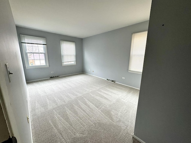 carpeted empty room with visible vents and baseboards