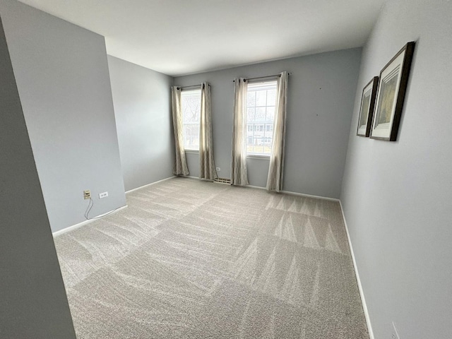 spare room featuring light colored carpet and baseboards