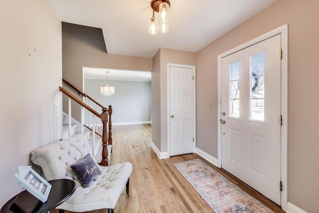 foyer with baseboards, light wood-style flooring, and stairs