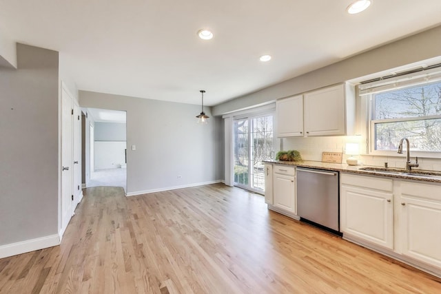 kitchen featuring stainless steel dishwasher, white cabinets, and a sink